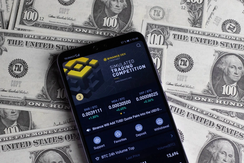dollars with cell phone showing Binance platform